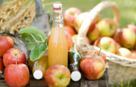 Äpfel und eine Flasche Apfelsaft auf einem Holztisch.